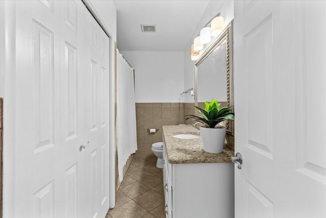 bathroom featuring vanity, tile walls, tile patterned floors, and toilet