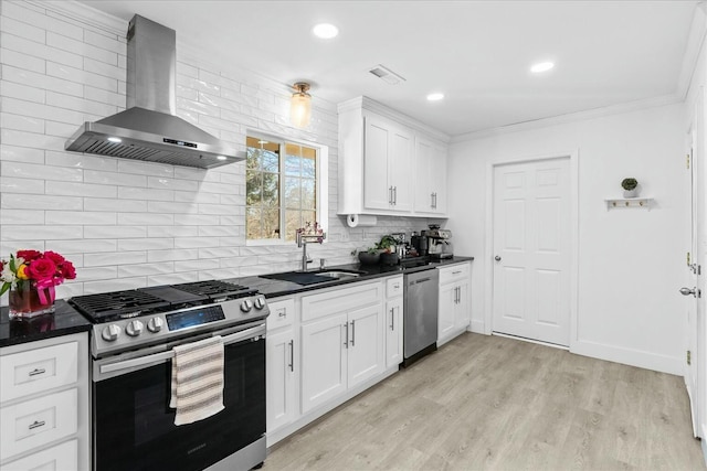 kitchen with stainless steel appliances, sink, white cabinets, and wall chimney exhaust hood