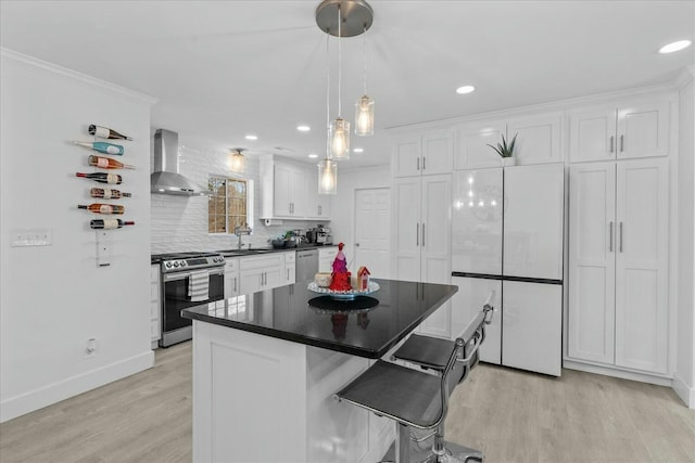 kitchen featuring appliances with stainless steel finishes, white cabinetry, sink, light hardwood / wood-style floors, and wall chimney exhaust hood