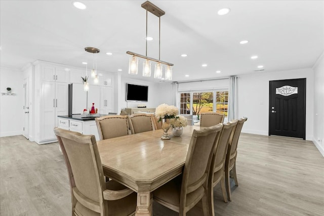 dining space featuring crown molding and light wood-type flooring