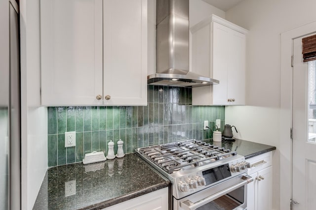 kitchen with stainless steel gas stove, white cabinets, dark stone counters, and wall chimney exhaust hood