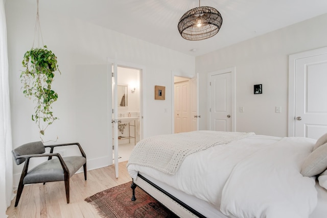 bedroom with connected bathroom and light hardwood / wood-style flooring