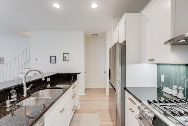 kitchen with sink, appliances with stainless steel finishes, white cabinetry, tasteful backsplash, and dark stone counters