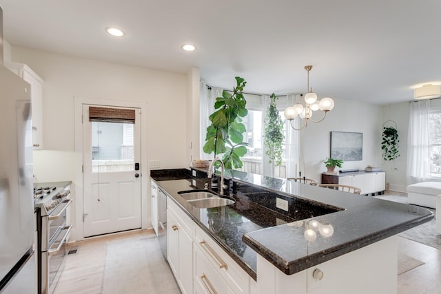 kitchen featuring sink, appliances with stainless steel finishes, white cabinetry, dark stone countertops, and a wealth of natural light