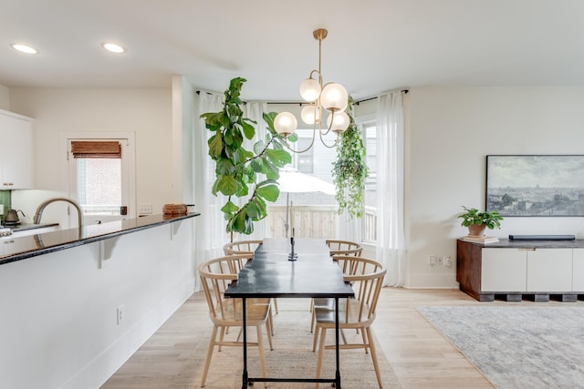 dining room with sink, a chandelier, and light hardwood / wood-style flooring