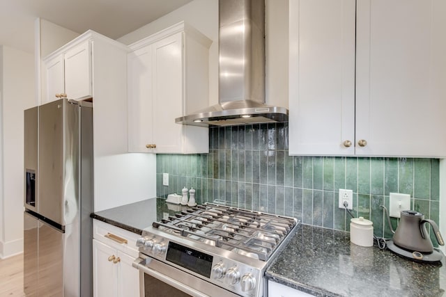 kitchen with stainless steel appliances, white cabinets, dark stone counters, and wall chimney exhaust hood