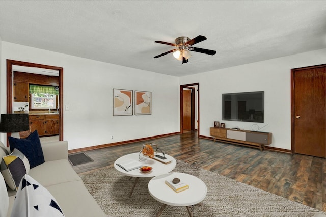 living room with dark wood-type flooring, a textured ceiling, and ceiling fan