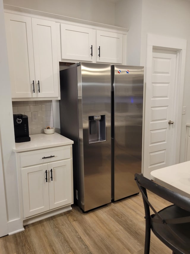 kitchen featuring decorative backsplash, white cabinets, light hardwood / wood-style floors, and stainless steel fridge with ice dispenser