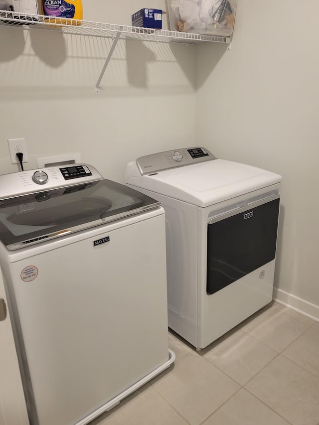 clothes washing area featuring separate washer and dryer and light tile patterned floors