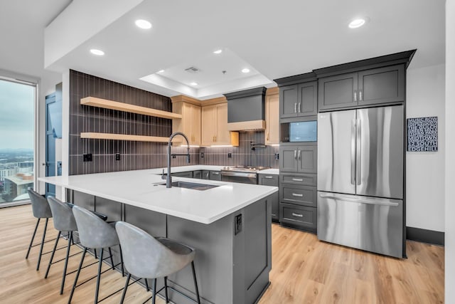 kitchen featuring stainless steel appliances, sink, a kitchen breakfast bar, and light hardwood / wood-style floors