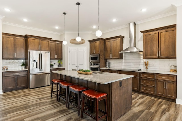 kitchen with a center island, decorative light fixtures, appliances with stainless steel finishes, wall chimney range hood, and a kitchen bar