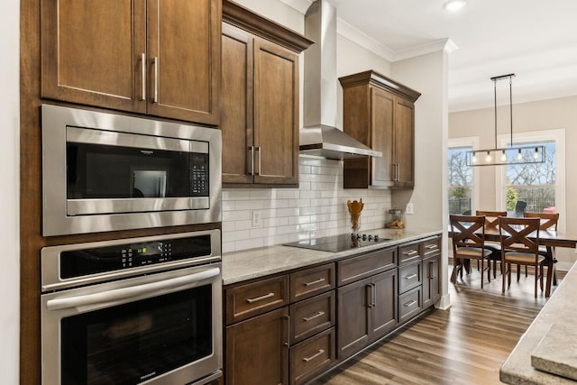 kitchen with appliances with stainless steel finishes, wall chimney range hood, crown molding, hardwood / wood-style flooring, and tasteful backsplash