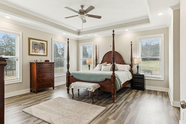 bedroom with wood-type flooring, crown molding, a tray ceiling, and ceiling fan