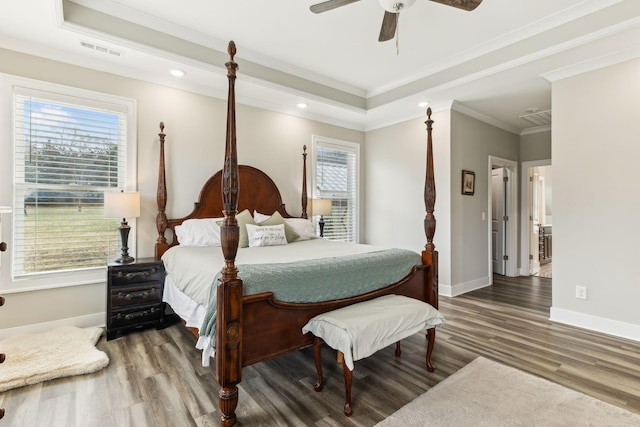 bedroom featuring a raised ceiling, crown molding, wood-type flooring, and ceiling fan