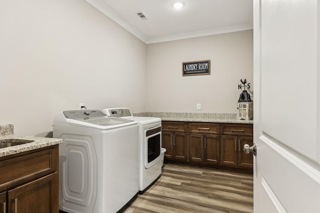 washroom featuring independent washer and dryer, crown molding, dark hardwood / wood-style flooring, sink, and cabinets