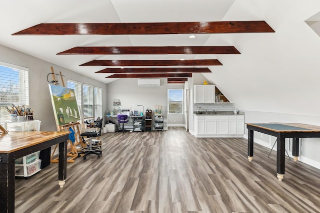 office featuring hardwood / wood-style flooring, lofted ceiling with beams, and a wall unit AC