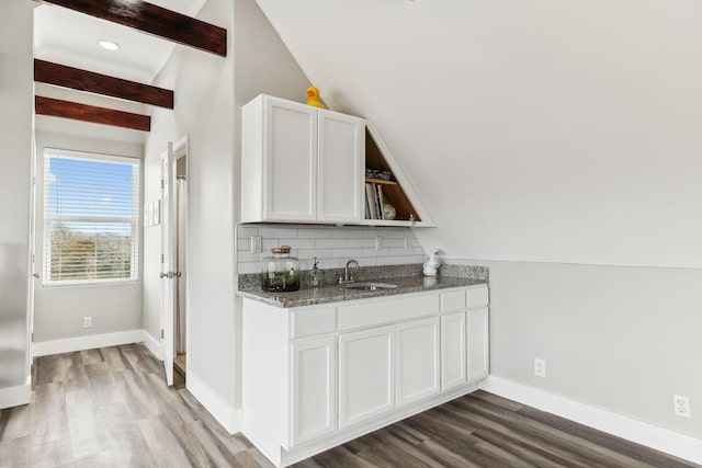 kitchen with sink, tasteful backsplash, lofted ceiling with beams, and white cabinets