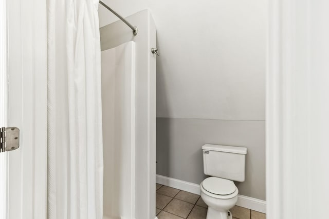 bathroom with tile patterned floors, toilet, vaulted ceiling, and a shower with curtain