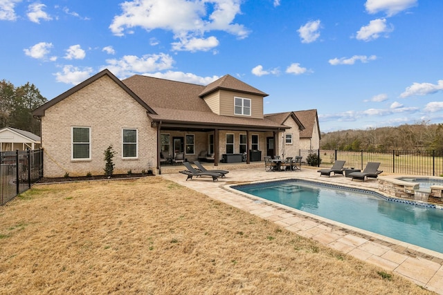 rear view of house featuring a pool with hot tub, a patio, and a yard