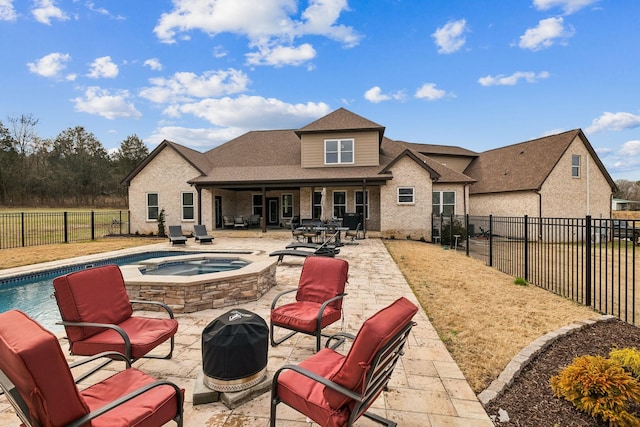 rear view of house featuring a patio and a swimming pool with hot tub