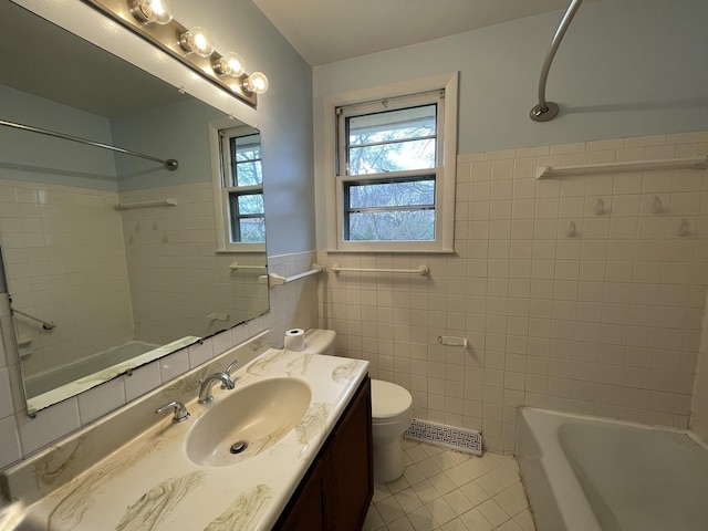 bathroom with tile patterned floors, vanity, toilet, and tile walls