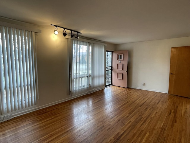 empty room featuring hardwood / wood-style flooring and track lighting