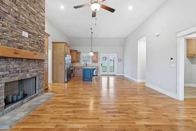 unfurnished living room featuring a high ceiling, sink, a large fireplace, and light hardwood / wood-style flooring