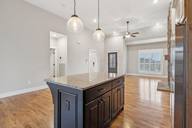 kitchen featuring light stone counters, light hardwood / wood-style flooring, stainless steel fridge, and a center island