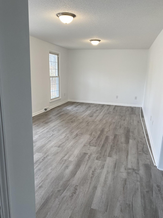 empty room with wood-type flooring and a textured ceiling