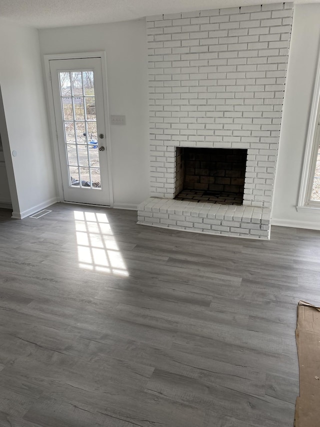 unfurnished living room featuring wood-type flooring, a fireplace, and a textured ceiling