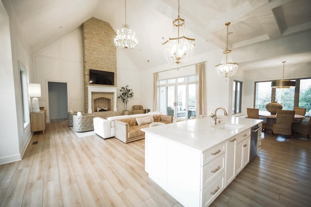 kitchen with pendant lighting, sink, white cabinetry, and a center island with sink