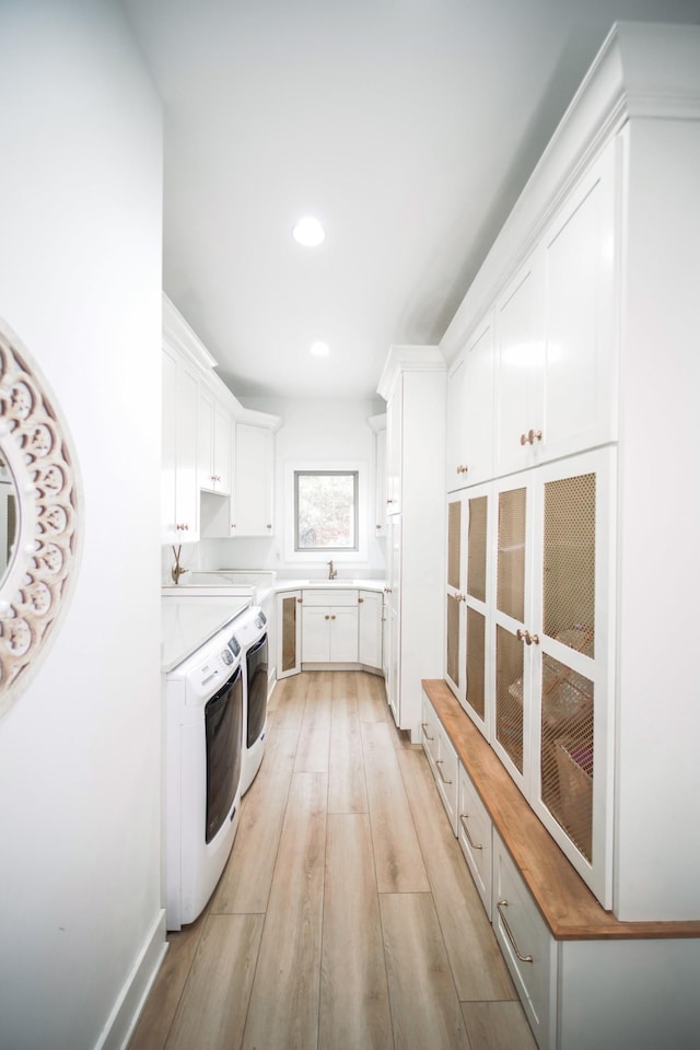 kitchen with white cabinetry, separate washer and dryer, sink, and light hardwood / wood-style flooring