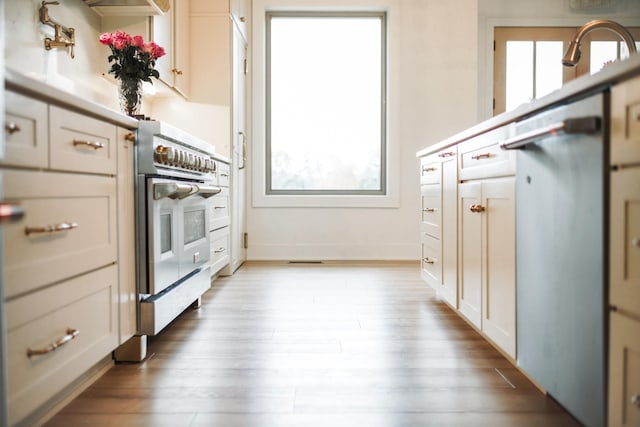 kitchen featuring dishwasher, sink, white cabinets, wall oven, and light wood-type flooring