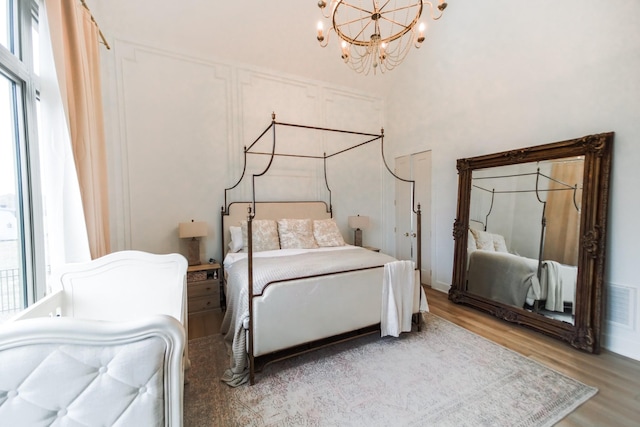 bedroom with a high ceiling, wood-type flooring, and a chandelier