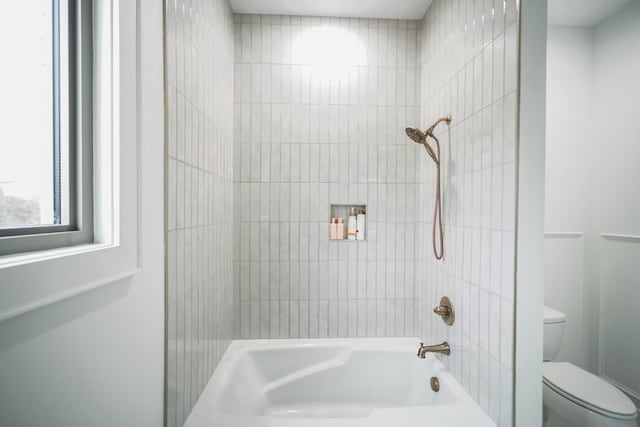 bathroom featuring tiled shower / bath combo and toilet