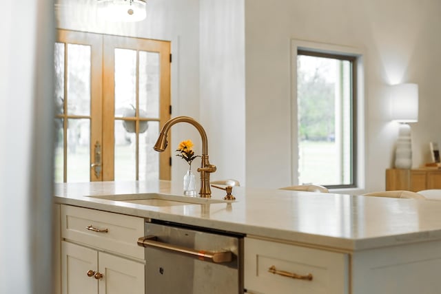 interior space featuring dishwasher, sink, and white cabinets