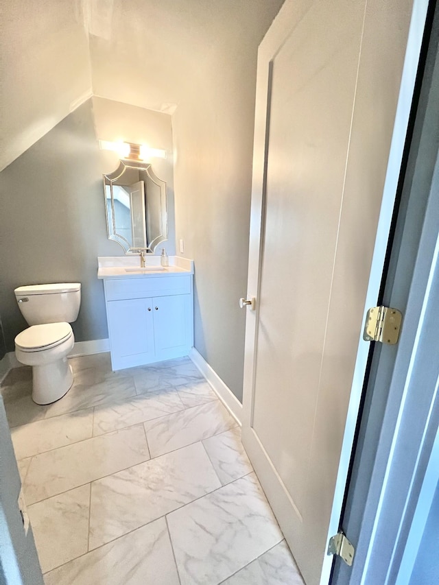 bathroom with lofted ceiling, toilet, and vanity