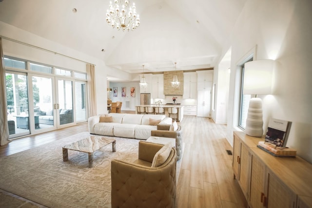 living room featuring light hardwood / wood-style flooring, high vaulted ceiling, and a chandelier