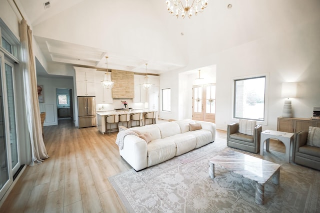 living room featuring high vaulted ceiling, light hardwood / wood-style flooring, and a notable chandelier