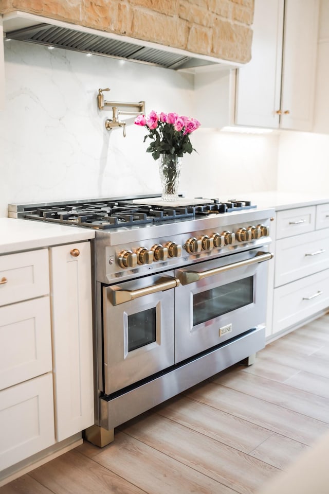 kitchen with double oven range, decorative backsplash, custom exhaust hood, and white cabinets