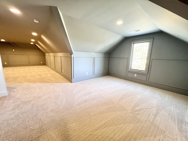 bonus room with lofted ceiling and light carpet