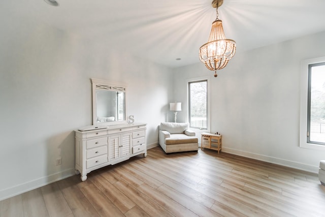 unfurnished room featuring an inviting chandelier and light wood-type flooring