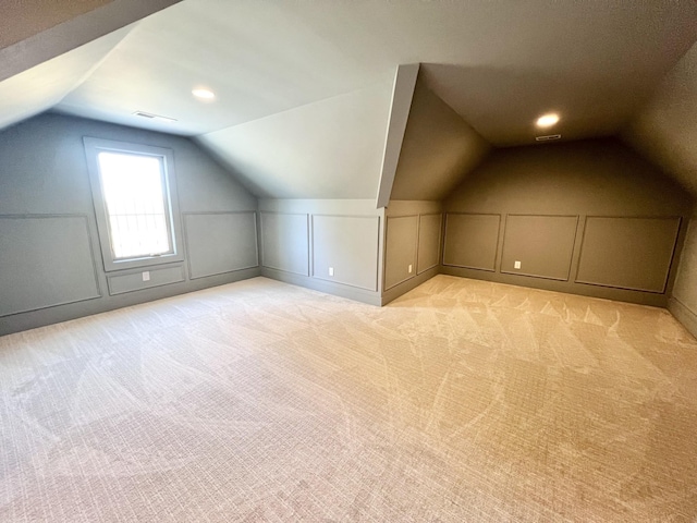 additional living space with light carpet and vaulted ceiling