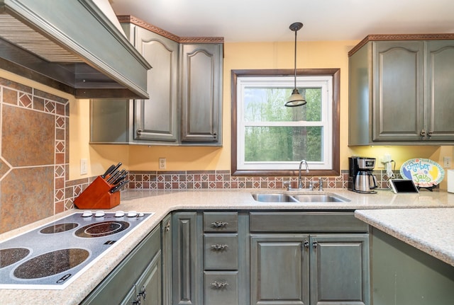 kitchen with tasteful backsplash, hanging light fixtures, stovetop, custom range hood, and sink