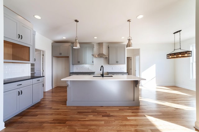 kitchen featuring hanging light fixtures, sink, gray cabinetry, and wall chimney exhaust hood