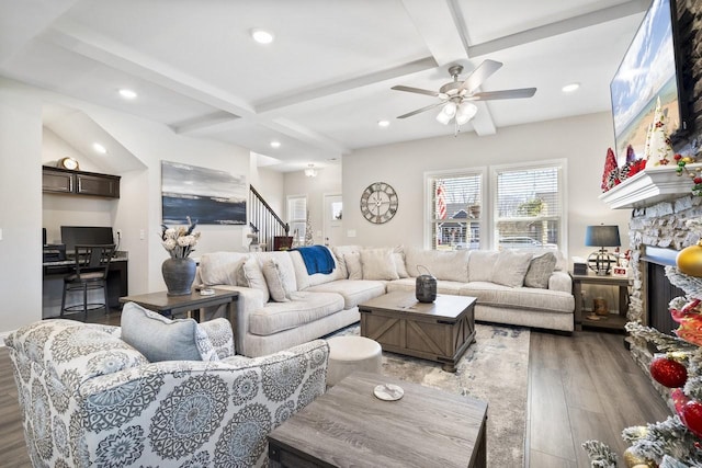 living room featuring coffered ceiling, a stone fireplace, dark hardwood / wood-style floors, and beamed ceiling