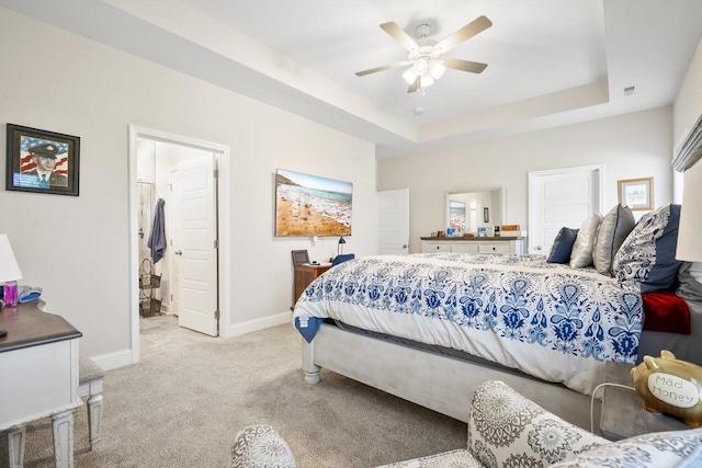 bedroom featuring ceiling fan, light colored carpet, and a tray ceiling