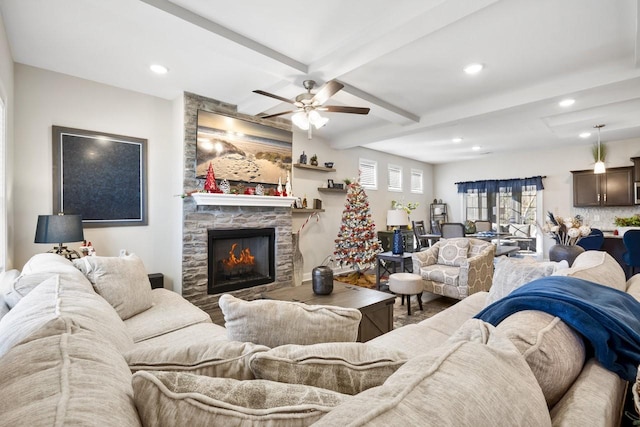 living room featuring hardwood / wood-style floors, beam ceiling, a stone fireplace, and ceiling fan