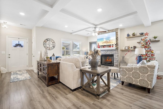 living room with hardwood / wood-style flooring, coffered ceiling, beam ceiling, and a stone fireplace