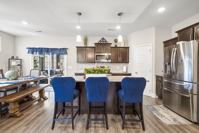 kitchen featuring pendant lighting, dark brown cabinets, a kitchen island, and appliances with stainless steel finishes